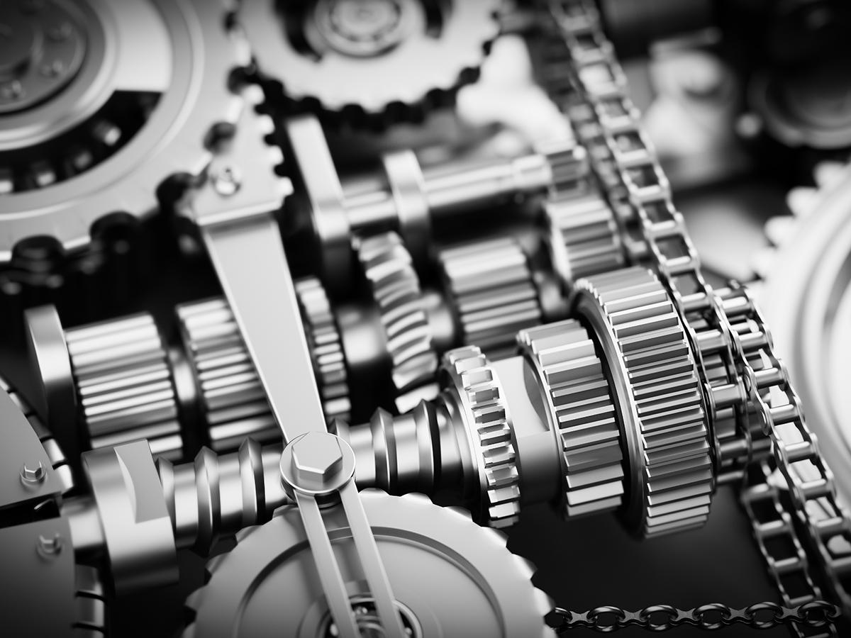 Close-up black-and-white image of interlocking gears, chains, and mechanical components.
