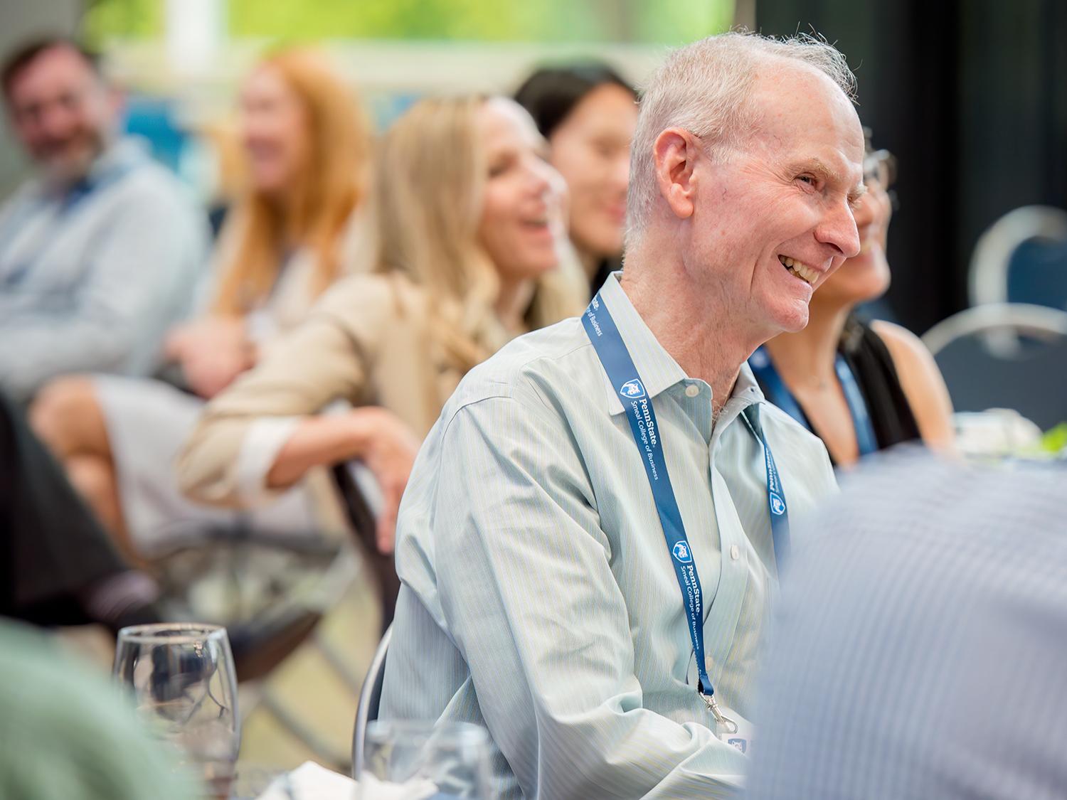 A smiling Don Hambrick sits in a room full of other smiling people.