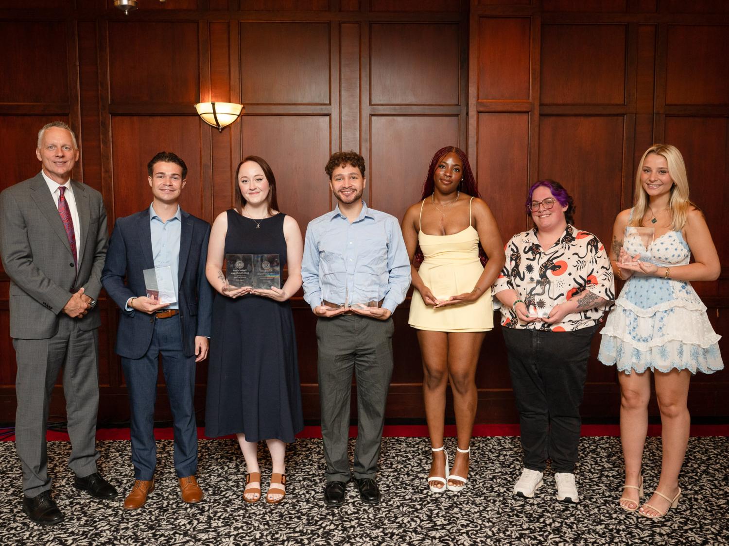 A group of people pose for a photo holding their awards