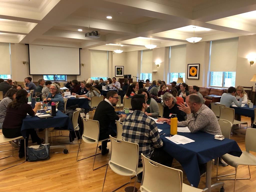 Several large groups sitting around tables during a tech-free teaching workshop