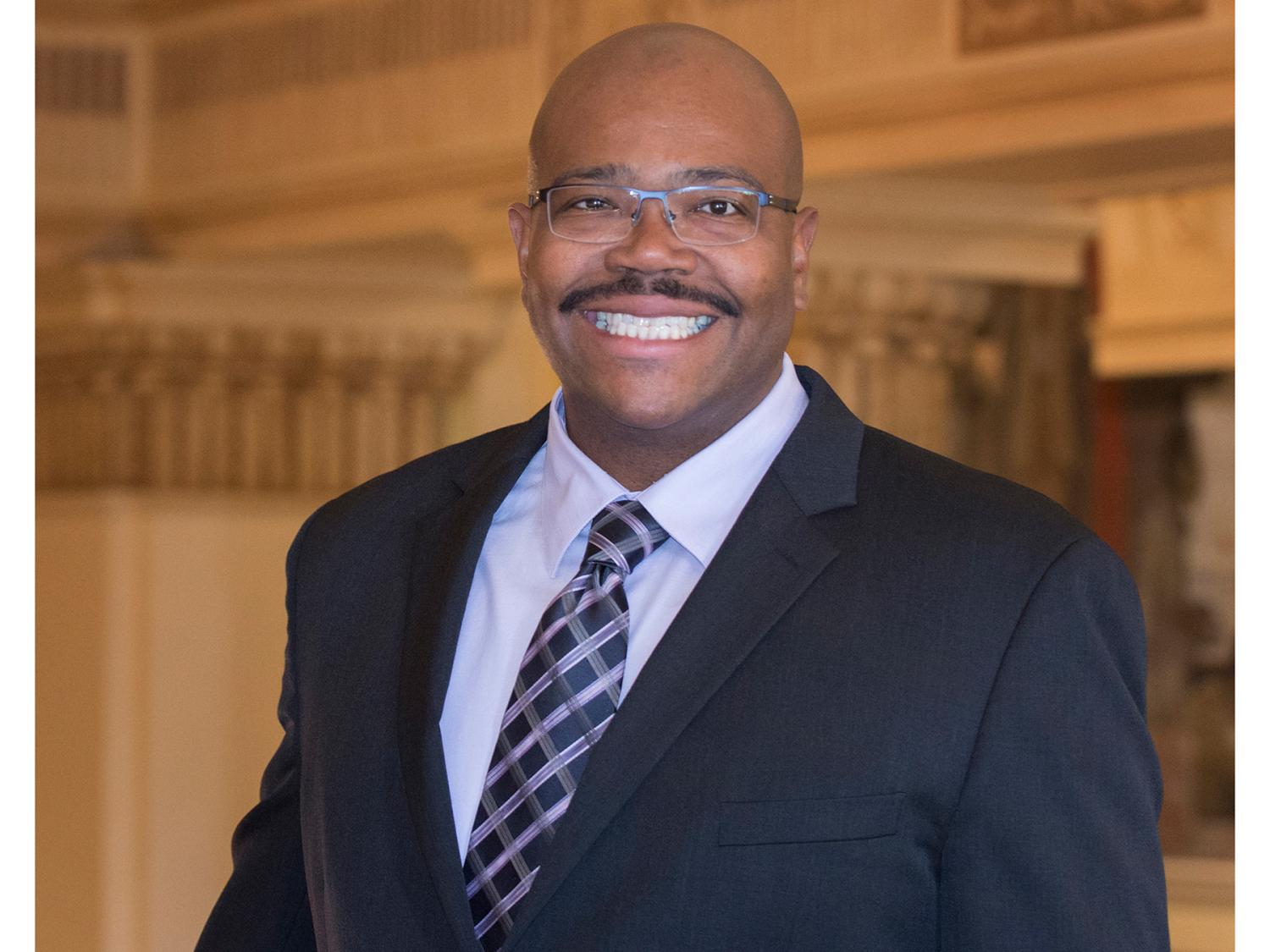 A smiling Lance Kennedy-Phillips wearing a business suit and tie