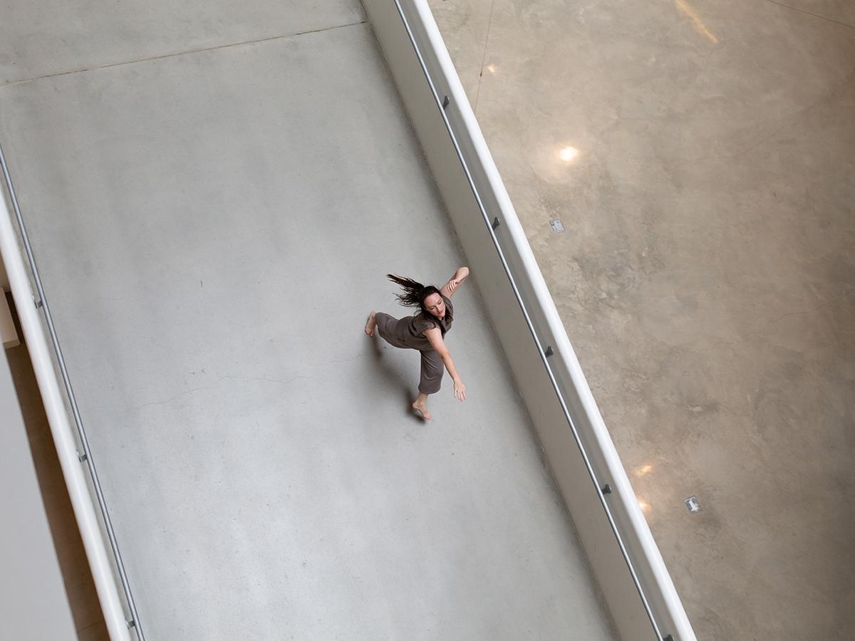 Lauren Linder dances barefoot in an indoor campus atrium.