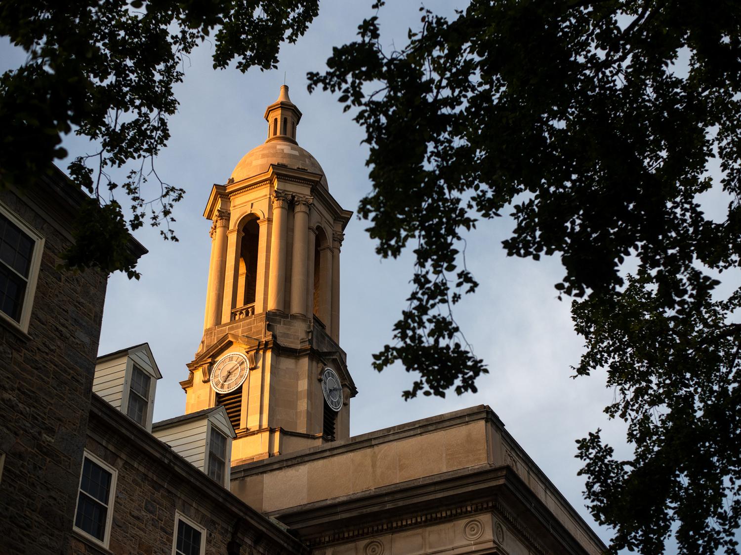 Old Main's bell tower lit up gold by the setting sun
