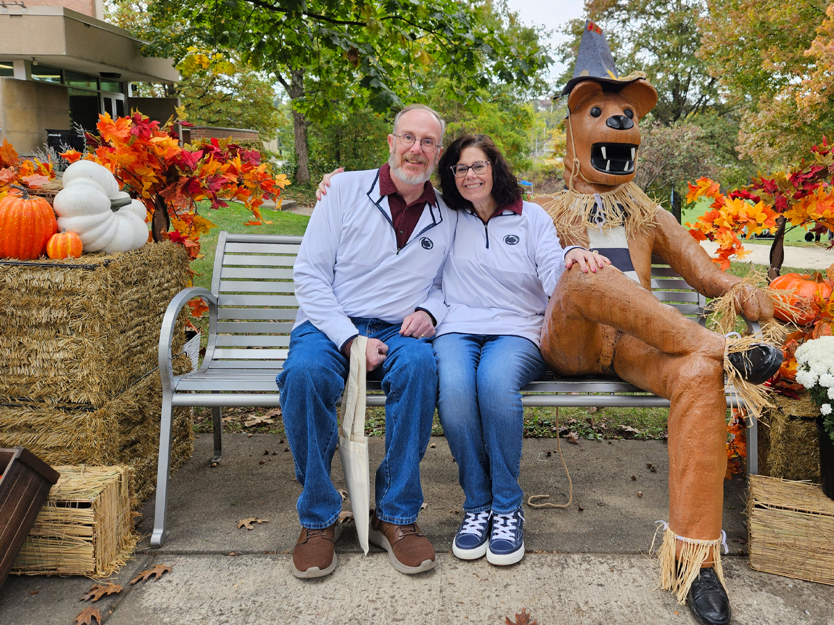 Donald and Victoria Garwood pose with the Nittany Lion amid a festive fall display at Penn State Greater Allegheny.