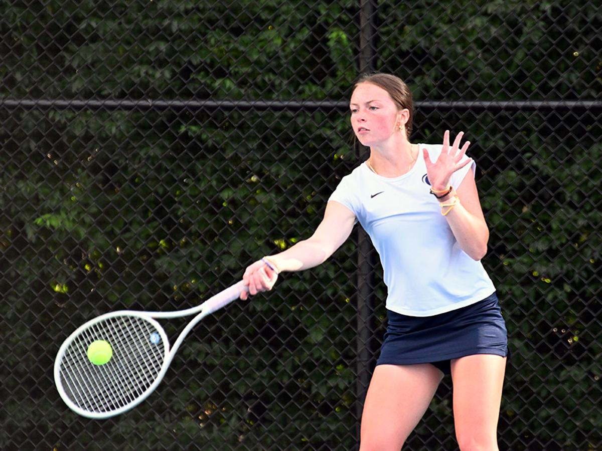 Sienna Fell, in a Penn State uniform, returns a tennis ball on an outdoor court.