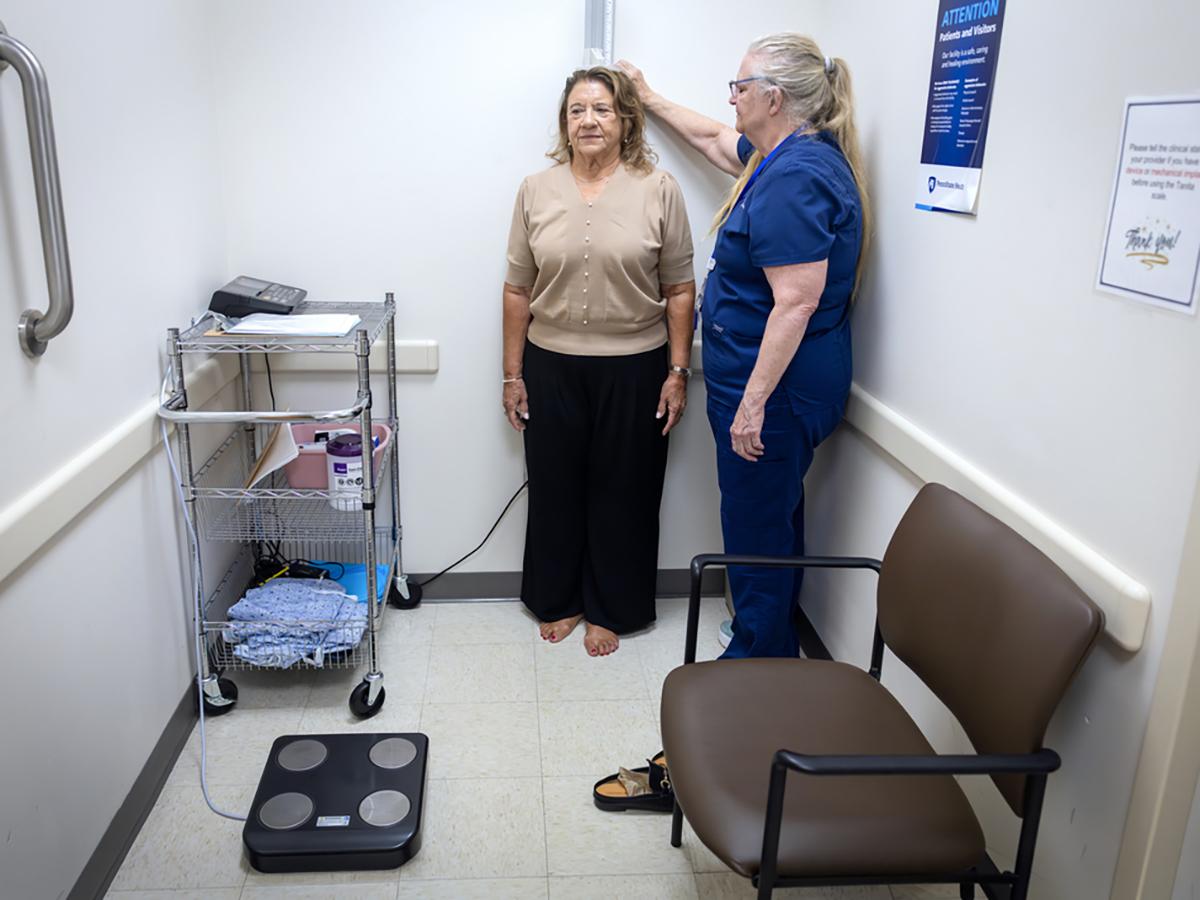 A woman gets her height measured by a medical assistant in a doctor’s office.