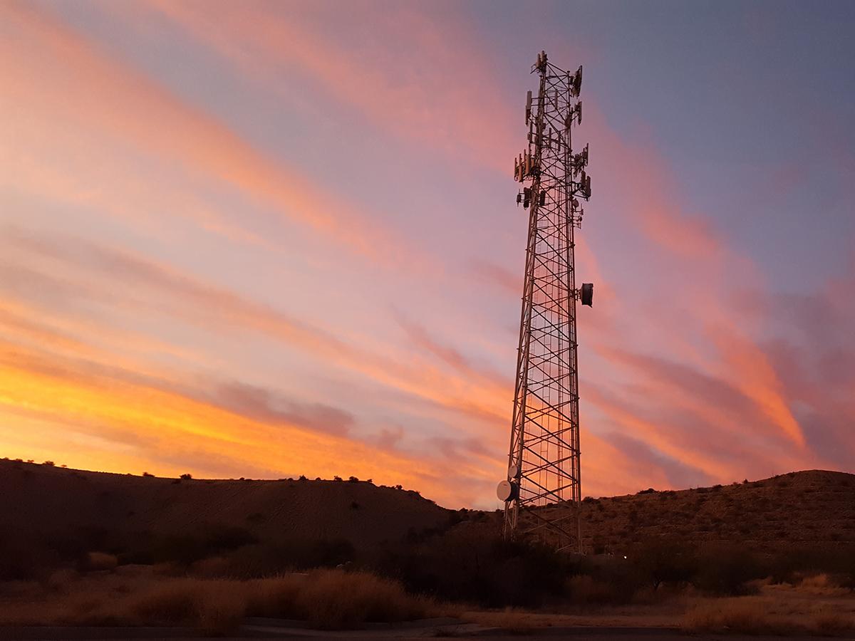 A communications tower with colorful sunset clouds