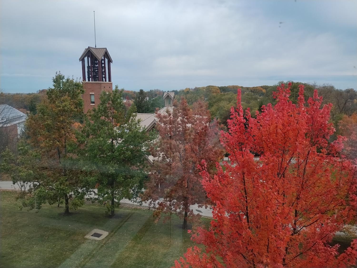 Fall photo overlooking college campus showing top of carillon tower and vibrant orange tree foliage