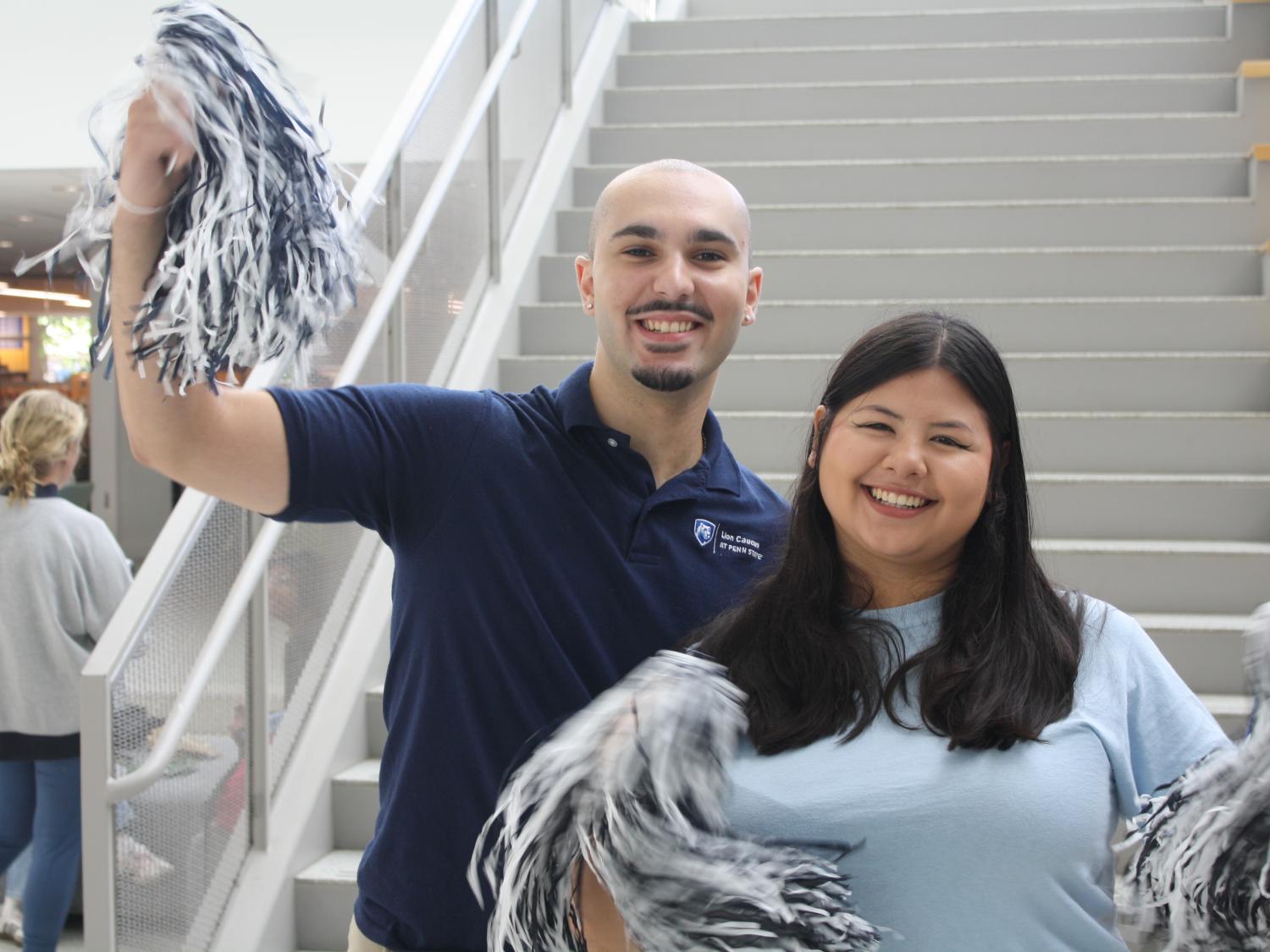 Two students holding blue and white pom poms at an event at Penn State University Park campus
