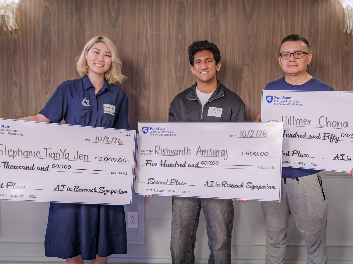 three people hold giant checks