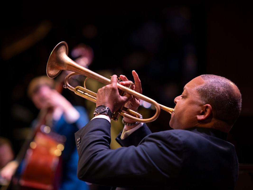 A Black man plays a trumpet.