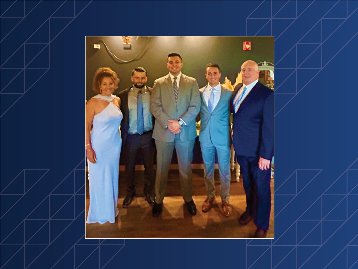 A group of five people posing in a room.