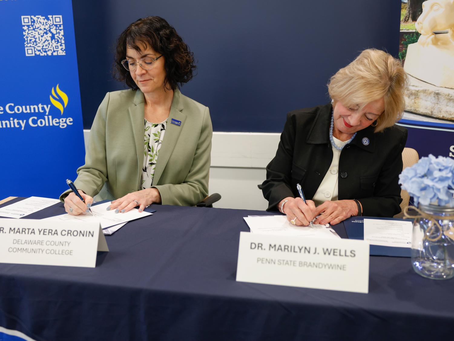 Two college leaders sign an agreement.