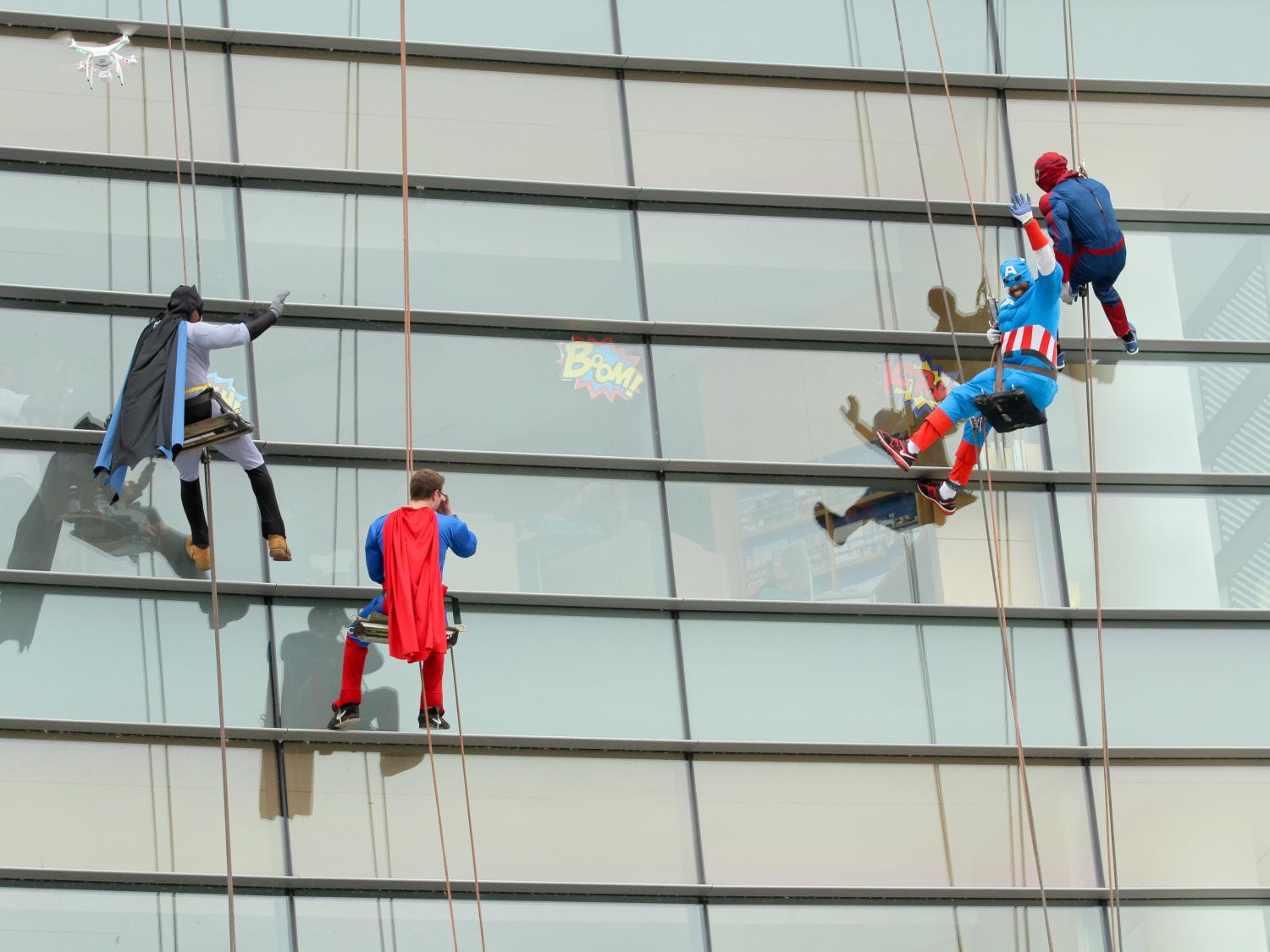 Four window washers dressed as superheroes descend from the top of Penn State Hershey Children's Hospital.