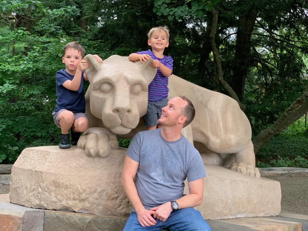 A man and his children pose at the Nittany Lion Shrine.