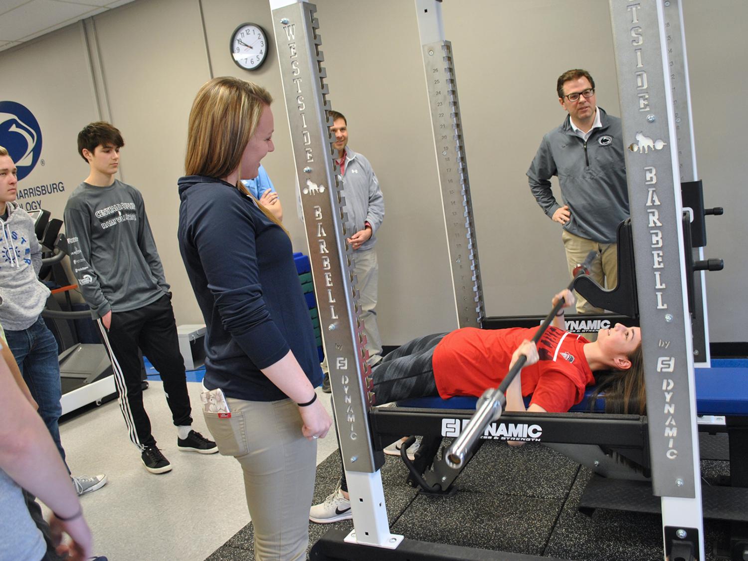 several people watching male on weight bench