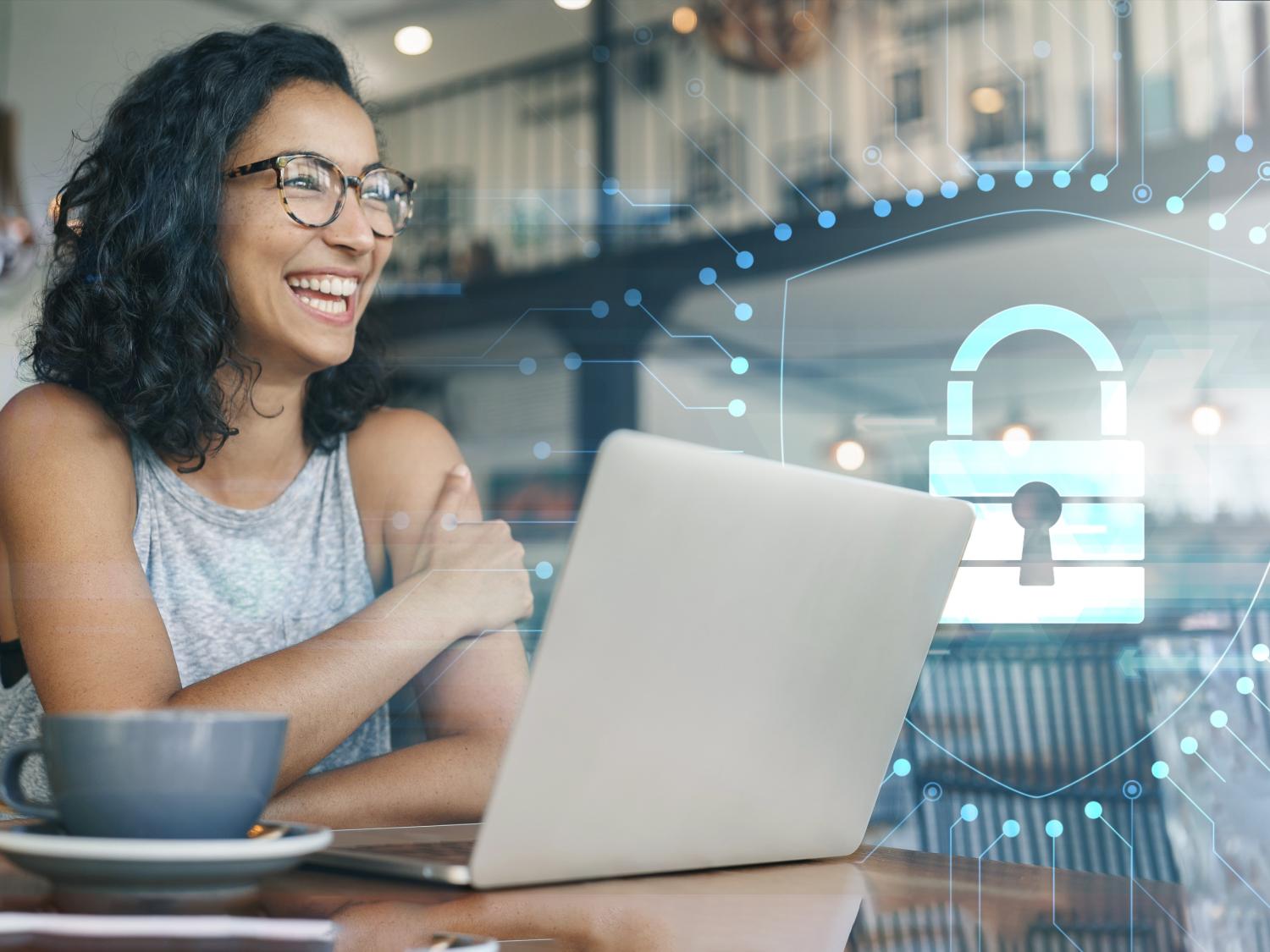 Student smiling in front of laptop with Security Shield overlay