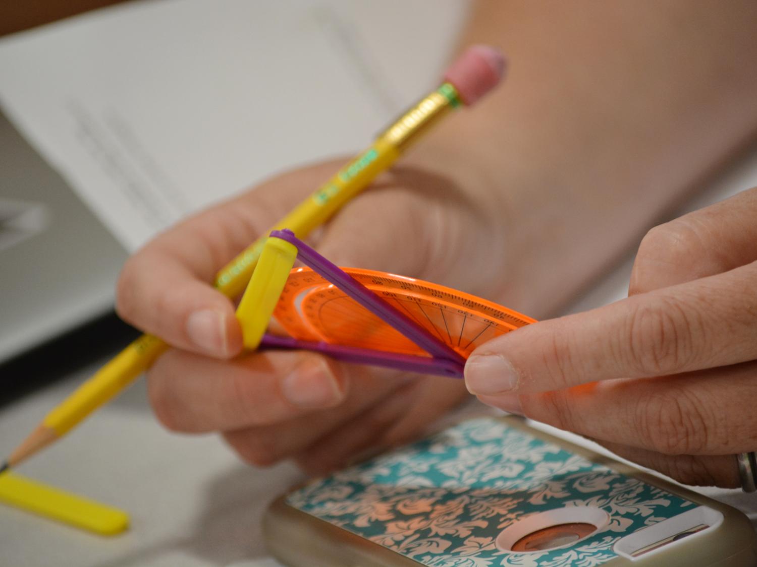 student hands with pencil and protractor
