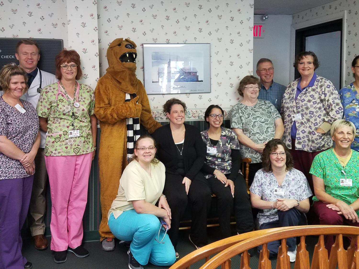 A group of people, including a mascot dressed as a lion, pose for a photo.
