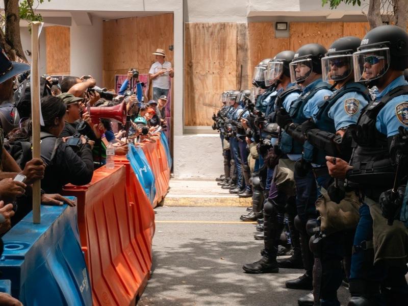 Protesters stand facing police officers in Puerto Rico