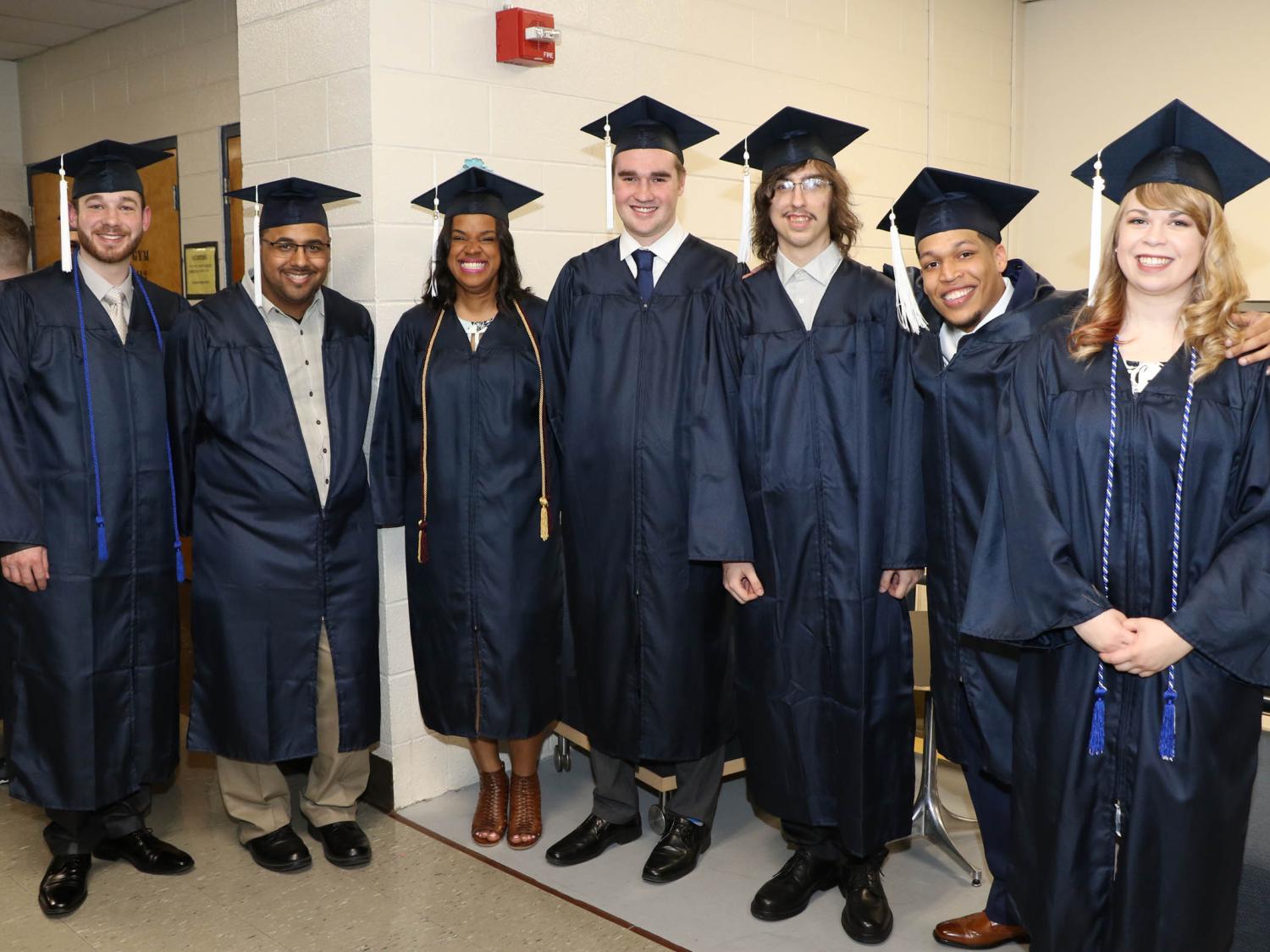 Seven smiling graduates in caps and gowns