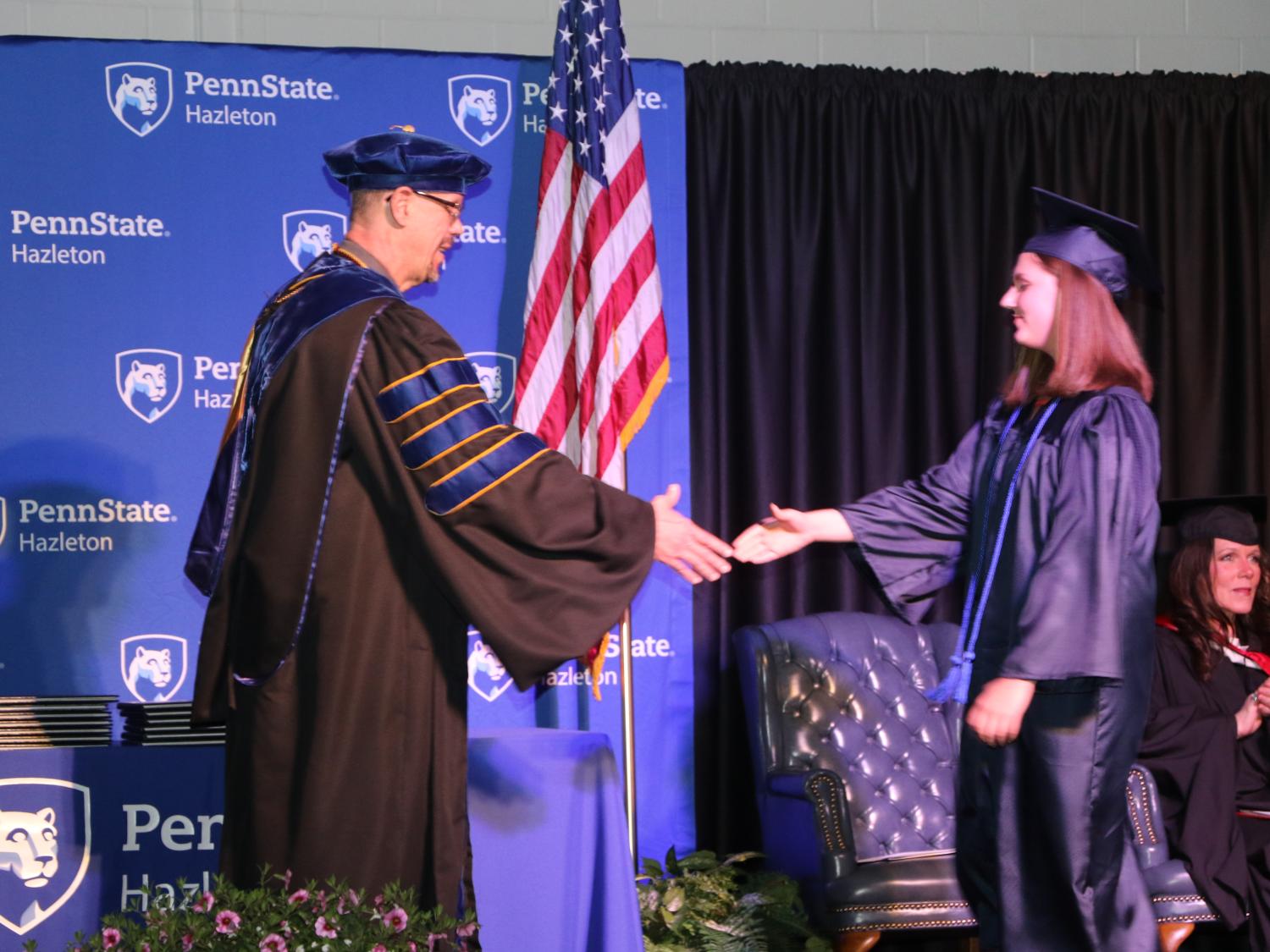 Graduate shakes hands with chancellor during commencement ceremony. 