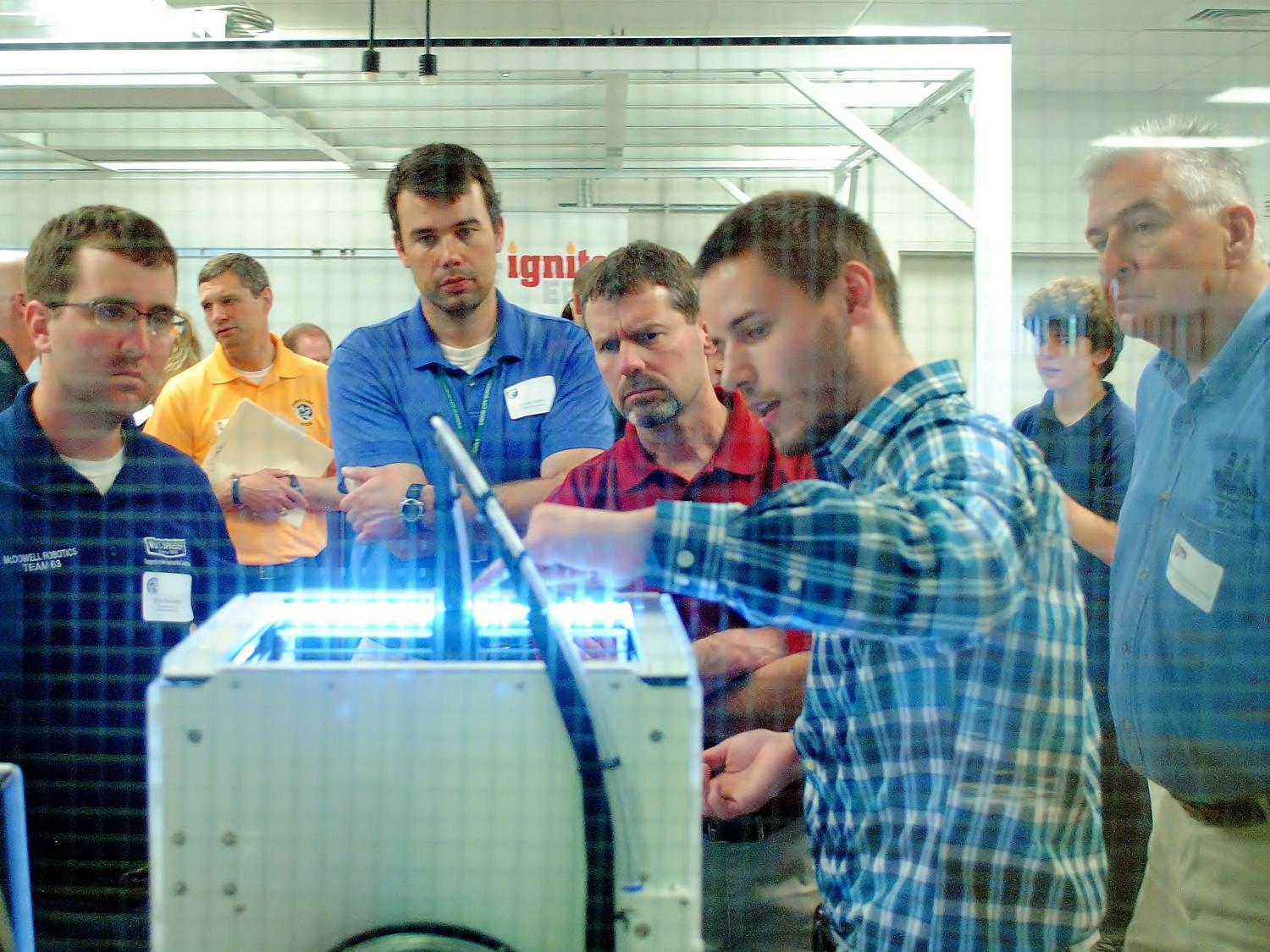 People look at a 3D printer at Penn State Behrend