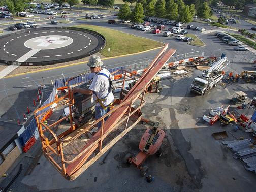 A man on construction equipment oversees construction on a medical center campus
