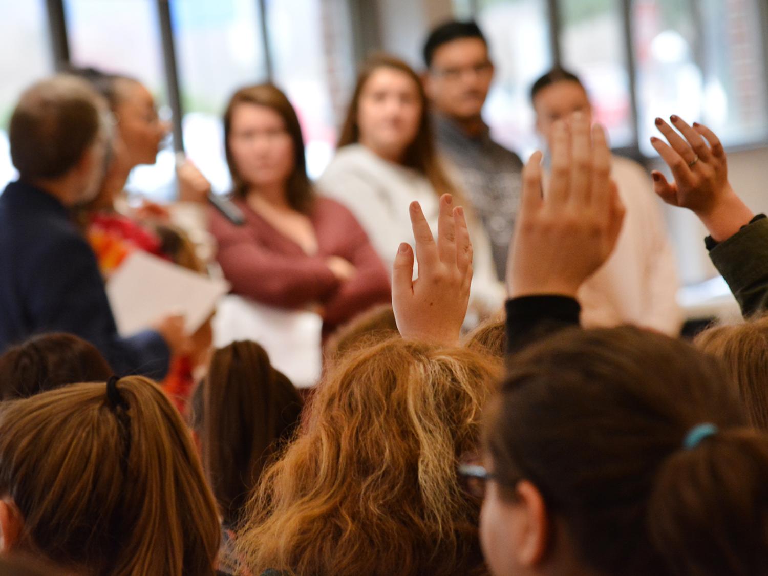 upraised hands at town hall meeting