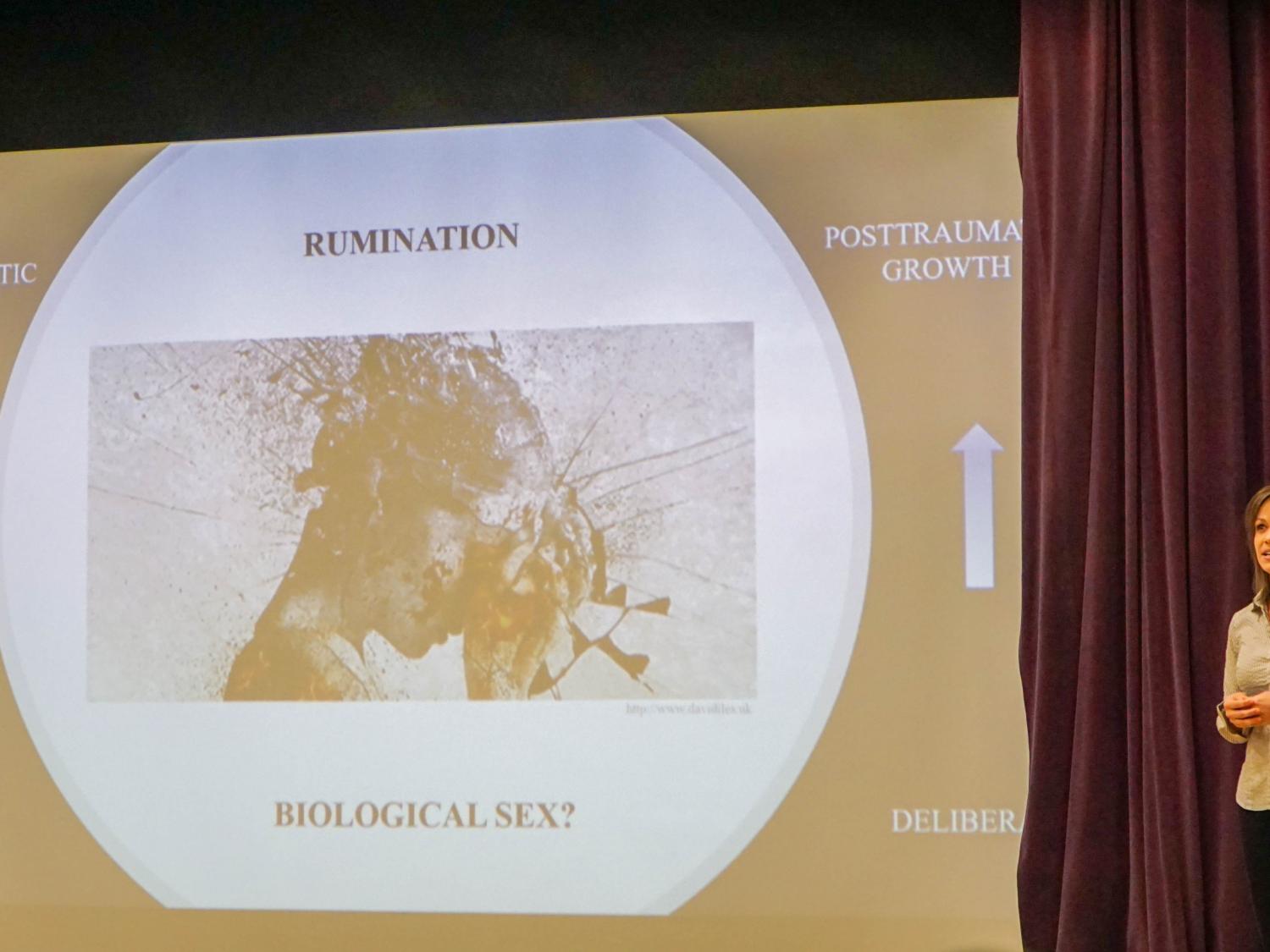 woman on stage in front of screen image