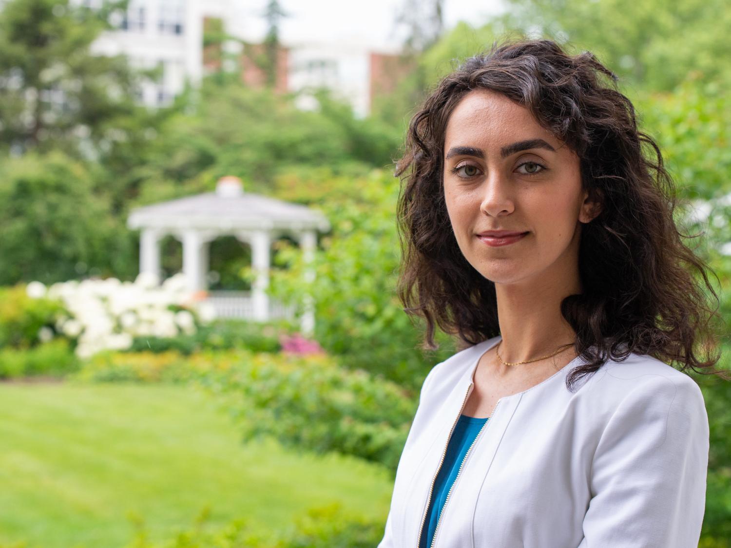 Melika Sharifironizi standing casually outdoors near the Alumni Building garden. 