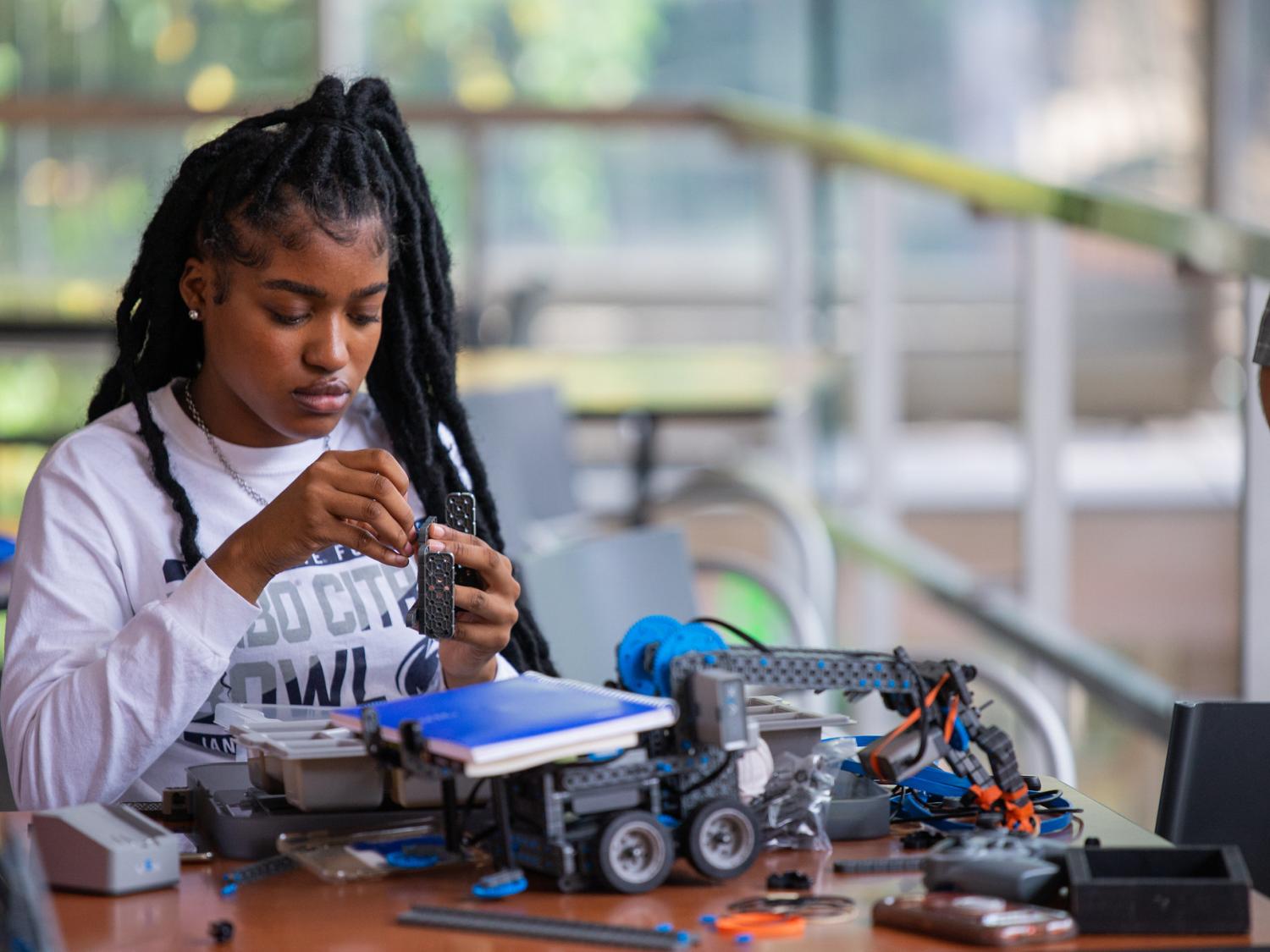 An engineering students works with a small robotic testing kit.