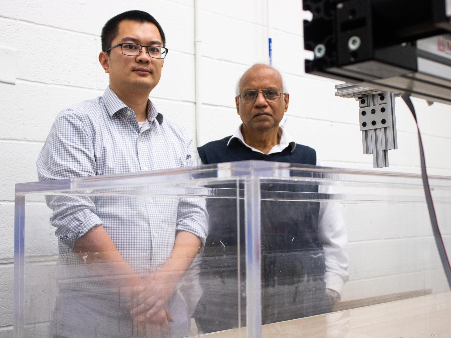 Two professors stand in front of a water tank in a laboratory. 