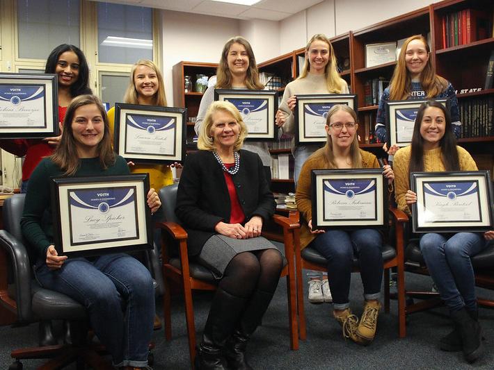 A group of undergraduate female students and a female administrator pose with certificates. 