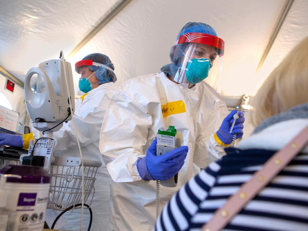 Images shows a healthcare worker in protective gear treating a patient