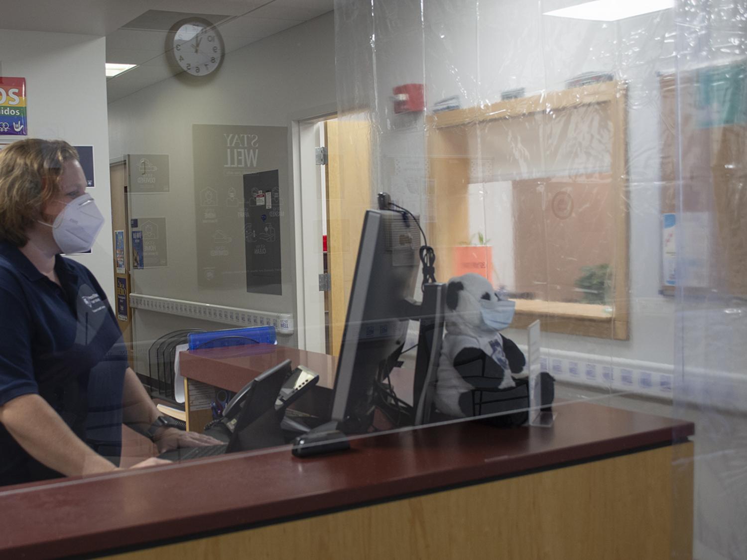 woman behind plastic barrier at desk