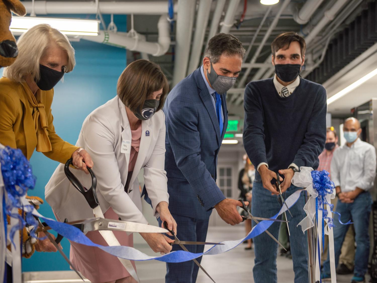 Four people cut a ribbon in the ME Knowledge Lab. 