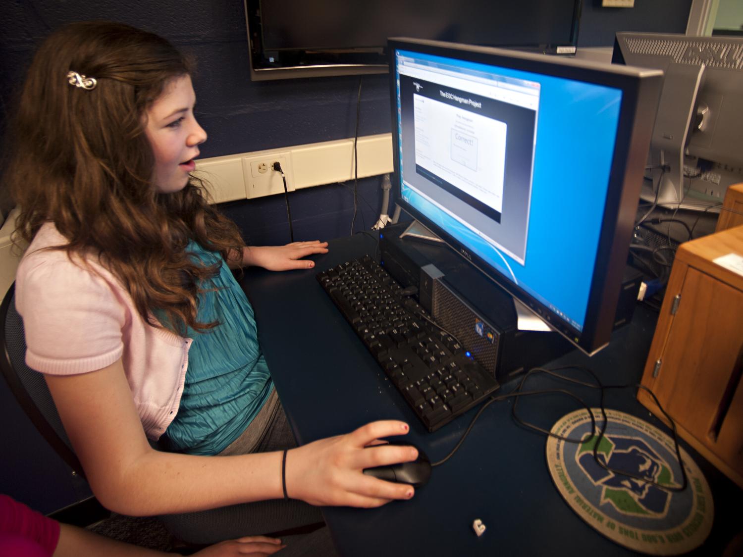 A girl plays a trivia game on a computer 
