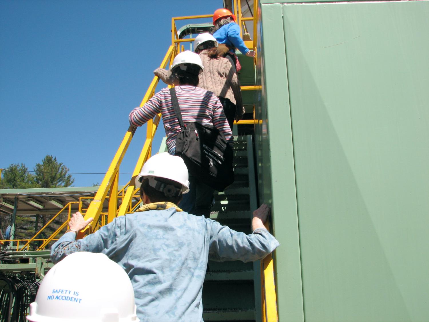Faculty members climb a drilling rig