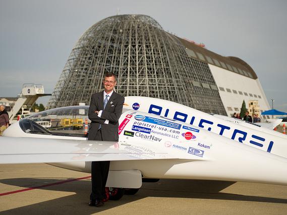 man smiling, leaning against plane