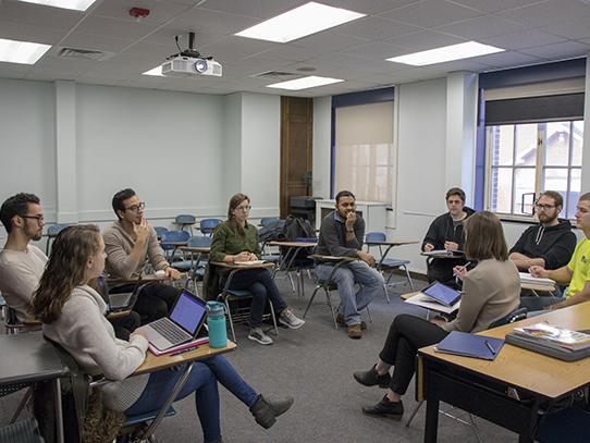 Students at desks gathered in a circle