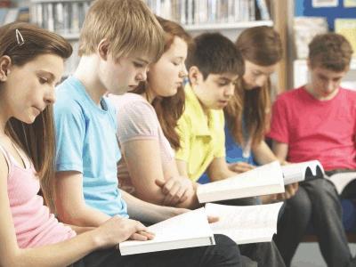 Teenage Students In Library Reading Books 