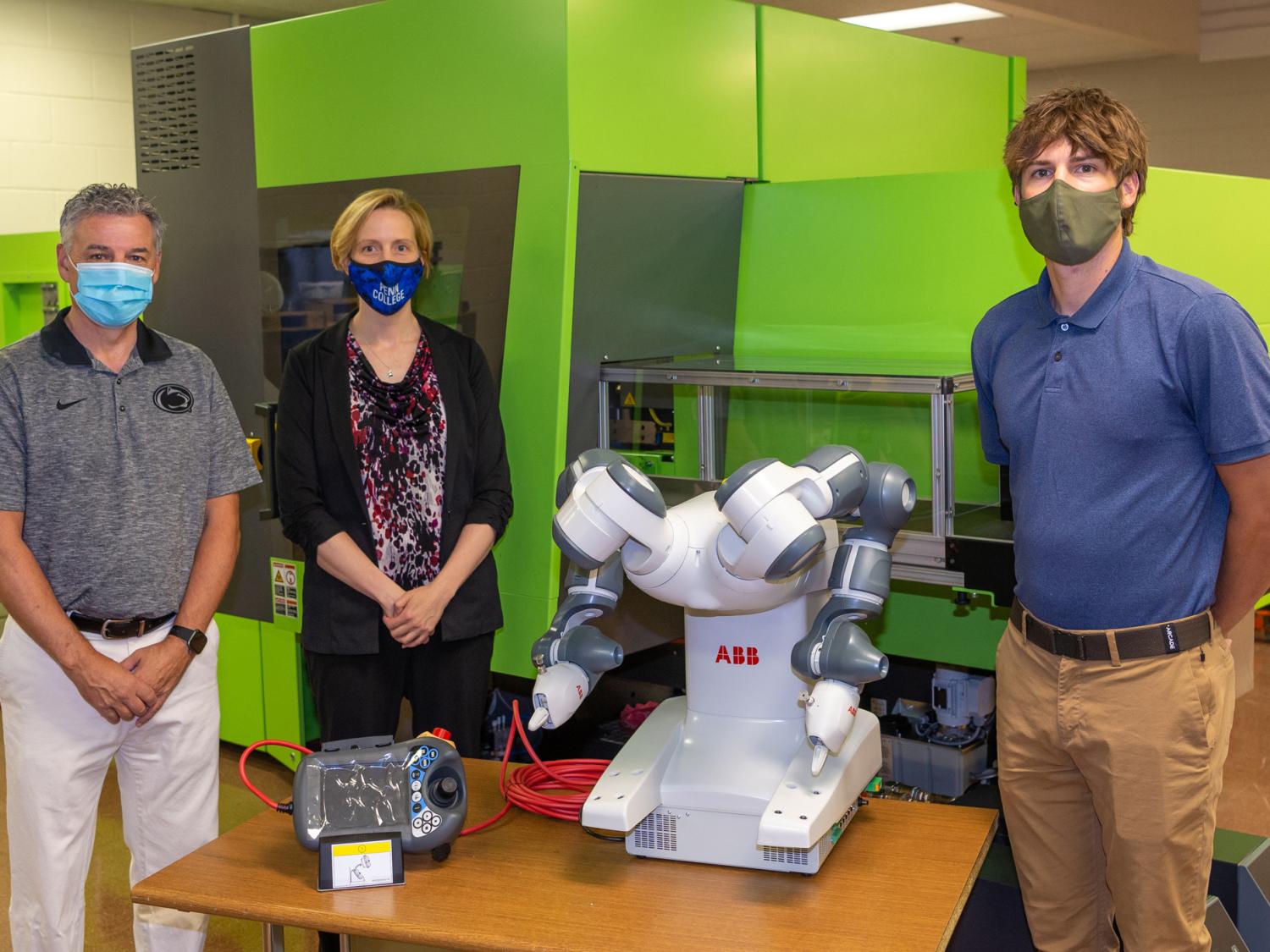 Three individuals stand next to a robot