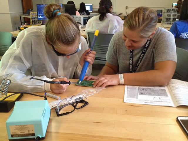 Two girls work on a project at the APOGEE camp