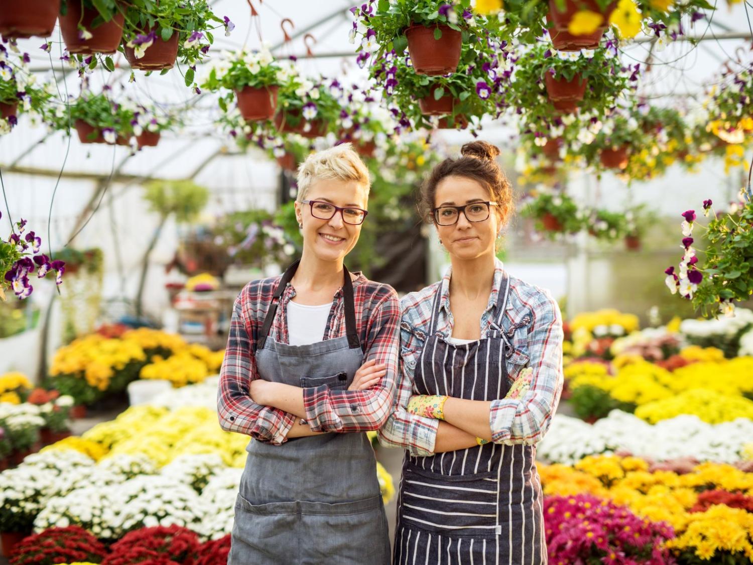 Two women pose in a floral-shop greenhouse