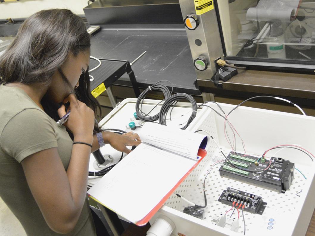 Undergraduate student Worlasie Djameh inspects the wiring configuration of the All-Seeing Eye device prior to installation.