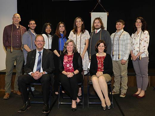 Group photo of 11 people, three sitting and eight standing. 