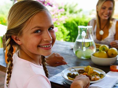 A girl sitting at a table smiles at the camera.