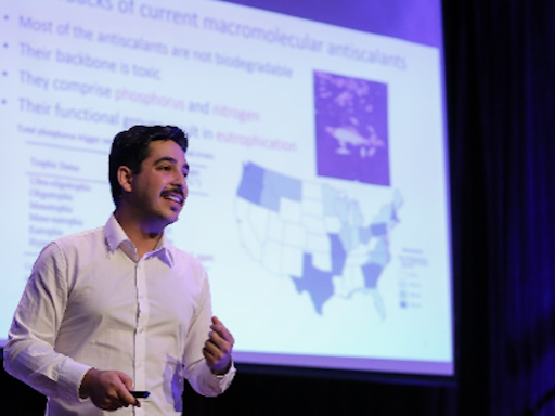 Man standing in front of large screen smiling and presenting