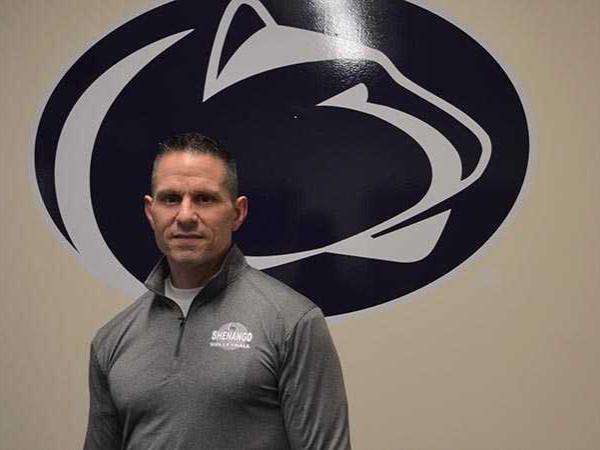 Man stands in front of the Nittany Lion Athletic mark
